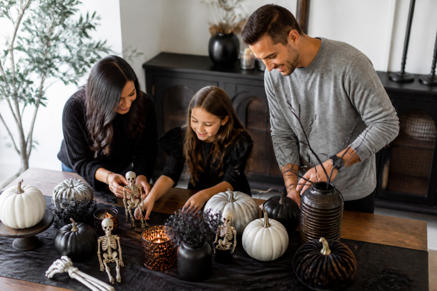 Adults child decorating halloween table skeleton pumpkins