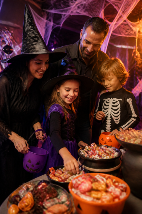 Costumed adults children halloween party food table